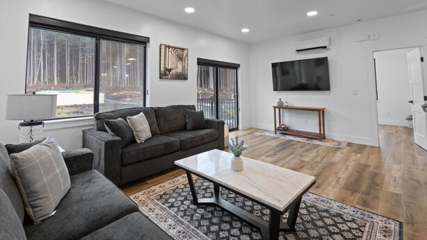 A modern living room with a sofa, coffee table, and a TV mounted on the wall. - Affordable Luxury With Views!  A305 (Juneau)