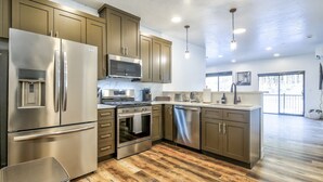 A modern kitchen with stainless steel appliances, wooden flooring, and a large island. - Affordable Luxury With Views!  A305 (Juneau)