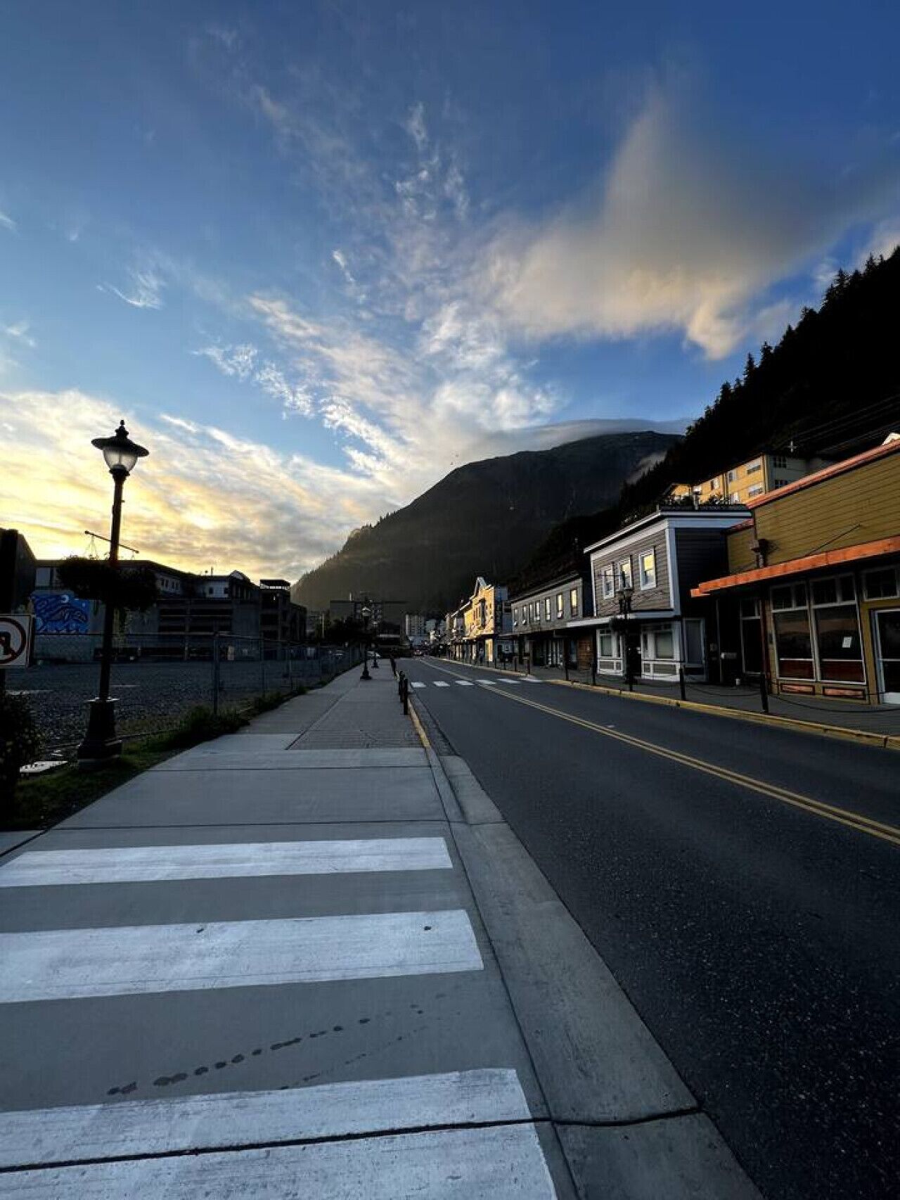 A street with buildings, a pedestrian crossing, and a mountain in the background.