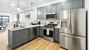 Una cocina moderna con armarios grises, electrodomésticos de acero inoxidable y suelo de madera.