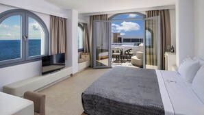 Een moderne hotelkamer met een groot bed, een televisie en een balkon met uitzicht op zee.