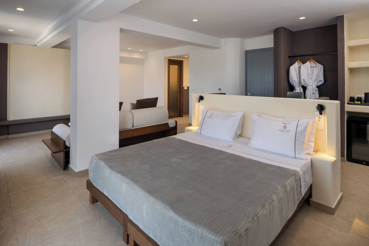 Ein modernes Hotelzimmer mit einem großen Bett, Nachttischen, einer Sitzecke mit einer Couch und einem Kleiderständer für Bademäntel.