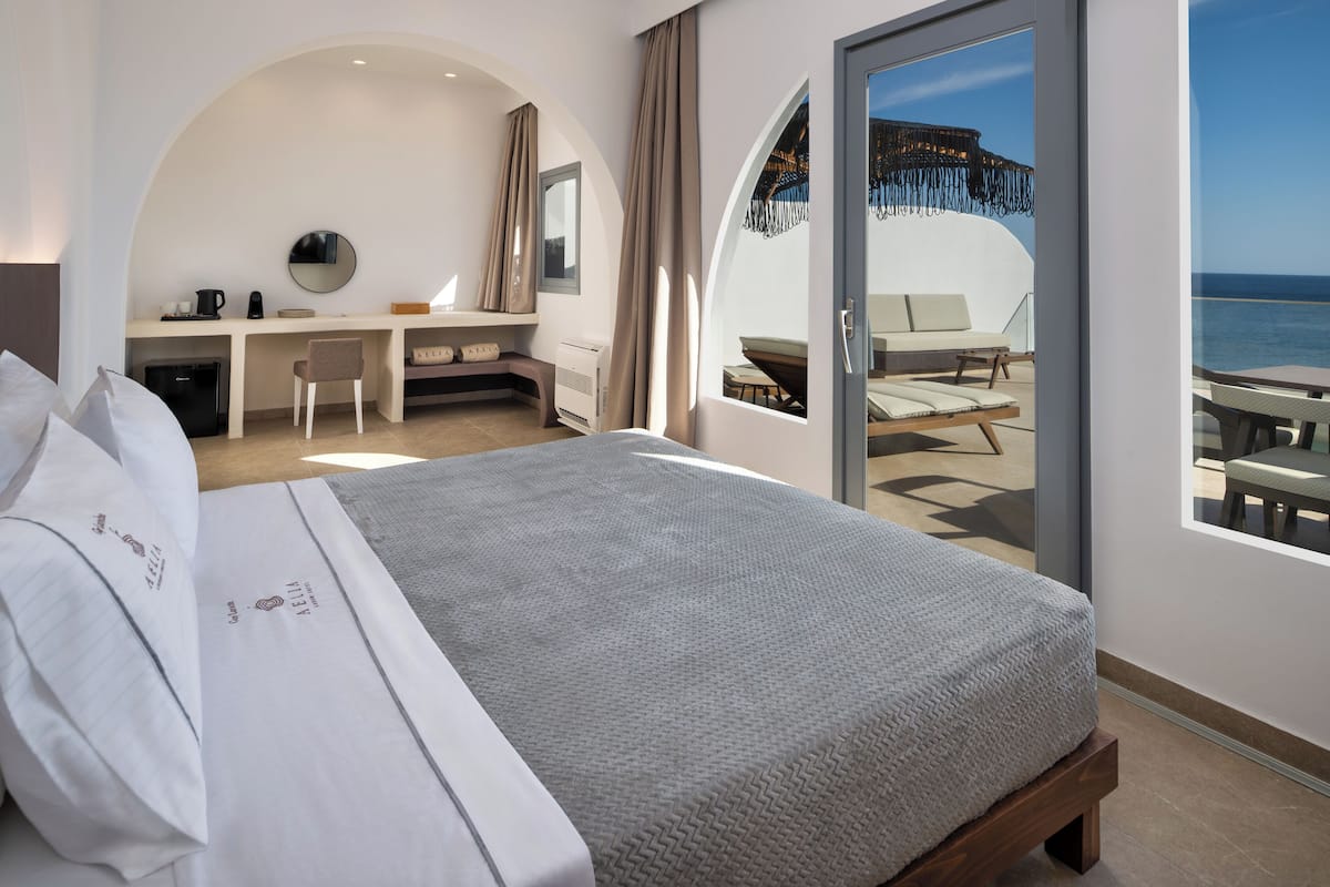 Ein modernes Hotelzimmer mit einem großen Bett, einem Schreibtisch und einem Balkon mit Meerblick.