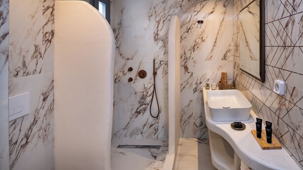 Een moderne badkamer met een witte badkuip, een douche en een wastafel met toiletartikelen.