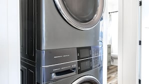 A modern, stainless steel front-loading washer and dryer unit in a residential setting.
