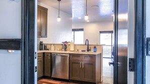 A modern kitchen with stainless steel appliances, wooden flooring, and pendant lighting. - Cozy, Spacious Retreat with Fireplace 205 (Juneau)
