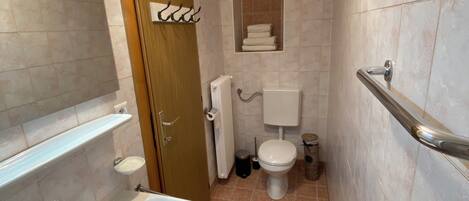 Un baño pequeño con lavamanos, inodoro y una ventana.