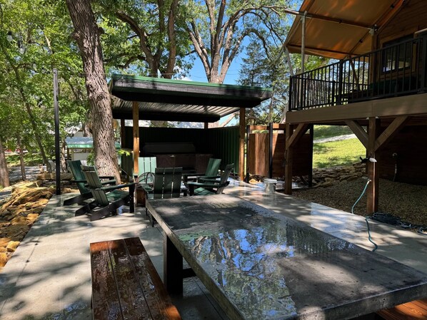 An outdoor patio area with a covered seating area, a pool, and a wooden deck.