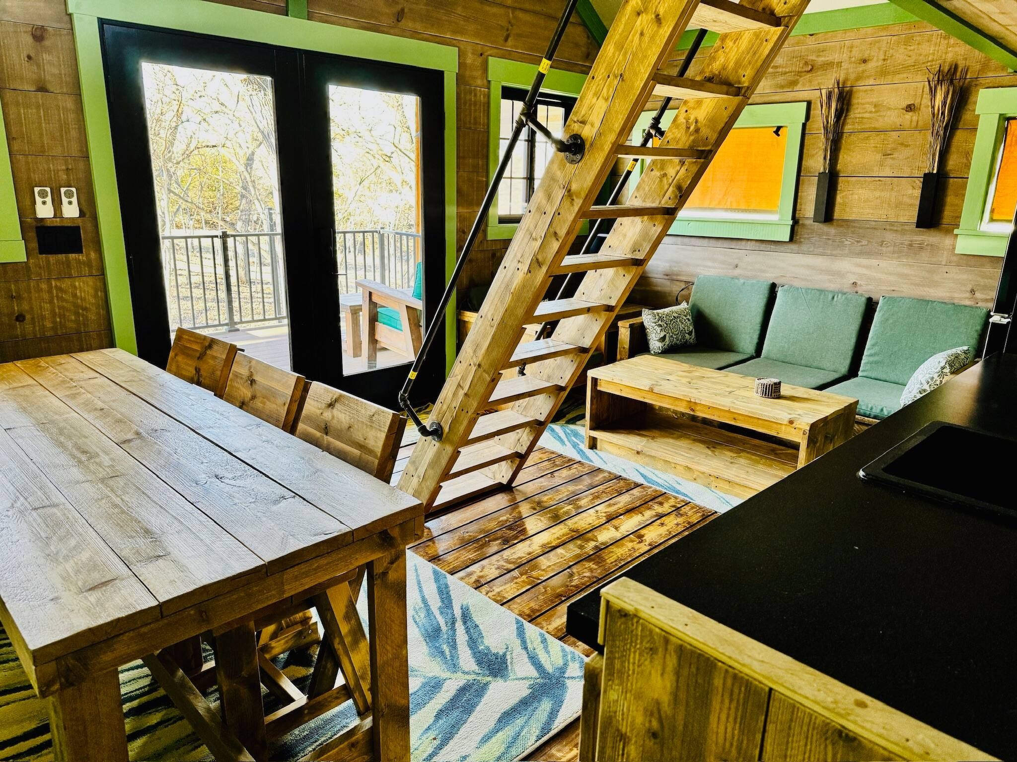 A wooden interior with a staircase, a dining table, and a sofa.