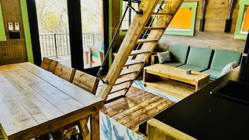 A wooden interior with a staircase, a dining table, and a sofa.