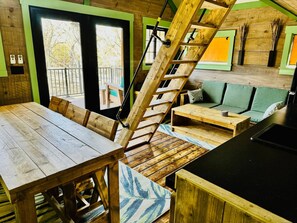 A wooden interior with a staircase, a dining table, and a sofa.