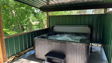 Un jacuzzi con un banco de madera en un área exterior cubierta.