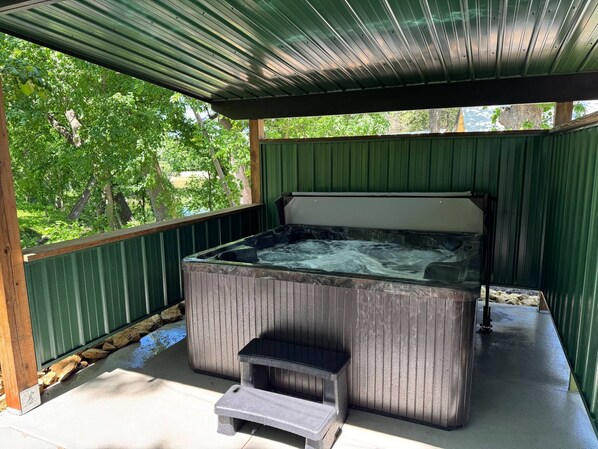 A hot tub with a wooden bench in a covered outdoor area.