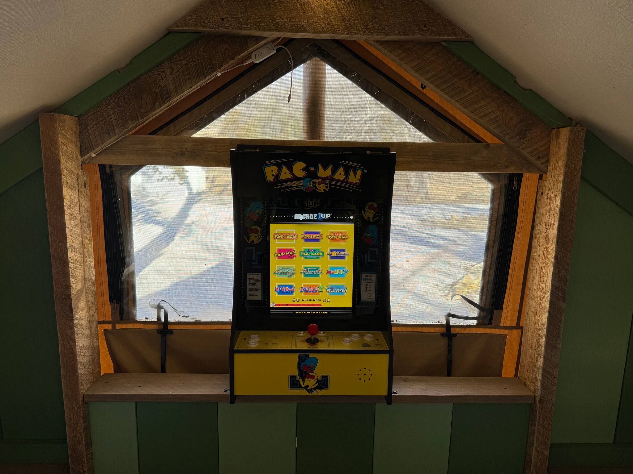 En Pac-Man arkadespil i et rum med skråvæg og et vindue.