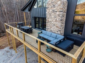 Eine Terrasse mit Gartenmöbeln, einer Steinmauer und einem großen Fenster.