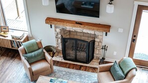 Una sala de estar acogedora con chimenea, dos sillones de cuero, una mesa de centro y una estantería.