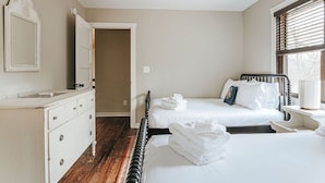 Un dormitorio con cama, mesita de noche, cómoda y ventana con persianas.