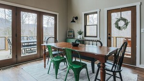 Un comedor con mesa y sillas de madera, ventanas amplias y vistas al exterior.