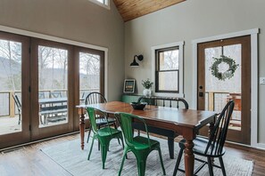 Un comedor con mesa y sillas de madera, ventanas amplias y vistas al exterior.
