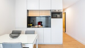 A compact kitchen with white cabinetry, a built-in oven, and a small countertop area. - GuestReady - Soothing Comfort in Aveiro (Aveiro)