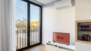 A modern hotel room with a sliding glass door to a balcony, a flat-screen TV, a built-in coffee maker, and a white console unit. - GuestReady - Soothing Comfort in Aveiro (Aveiro)