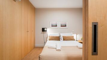 Habitación de hotel con cama, armario de madera y dos cuadros en la pared.
