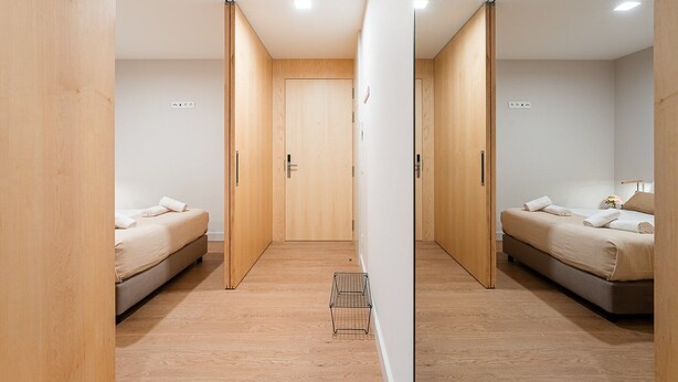 A modern hotel room with two beds, wooden flooring, and a central door. - GuestReady - Soothing Comfort in Aveiro (Aveiro)