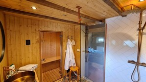 Une salle de bain aux murs lambrissés, dotée d’une cabine de douche en verre, d’un porte-serviettes et d’un lavabo.
