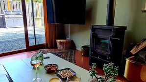 Un salon chaleureux avec une longue table dressée pour un repas, une cheminée et un téléviseur.