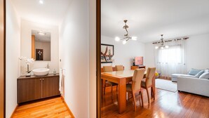 Un espace de vie moderne comprenant une table à manger en bois, des chaises, un canapé et une grande fenêtre avec des rideaux.