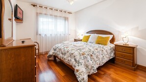 Une chambre à coucher avec un lit en bois, une table de chevet avec une lampe, une commode en bois et un miroir.