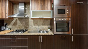 Une cuisine moderne avec des meubles en bois, une hotte en acier inoxydable, un four à micro-ondes encastré et un four double.
