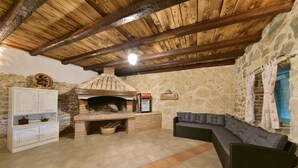 A stone-walled room with a brick fireplace, a white cabinet, and a dark-colored sofa. - Villa Lapis Zadar Villas (Donje Raštane)