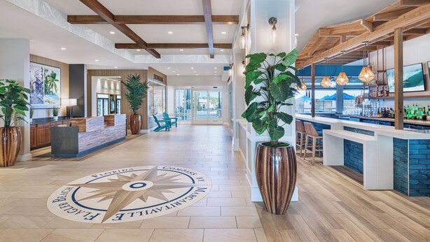A spacious lobby with wooden beams, a bar area, and a large compass floor design. - Compass Hotel Flagler Beach (Flagler Beach)