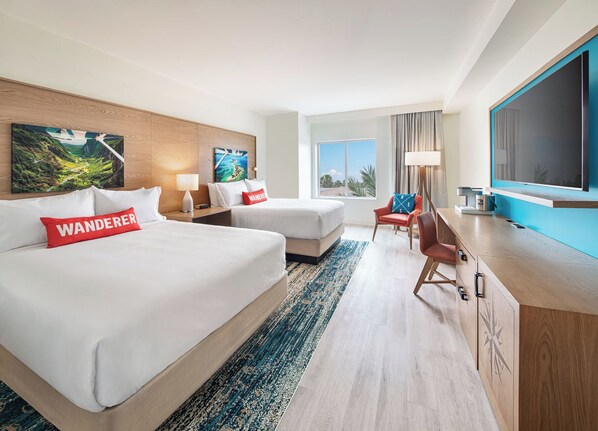 Habitación de hotel con dos camas, un escritorio, una silla y un ventanal grande.