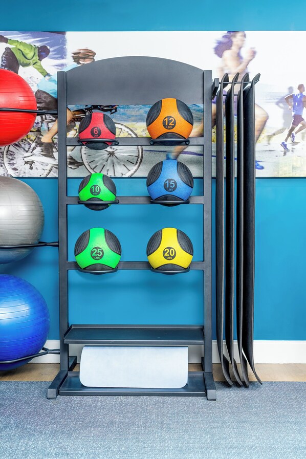 Un présentoir pour équipements de fitness contenant divers ballons d’exercice et poids.