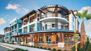 A multi-story hotel with outdoor seating, a covered patio, and a sign indicating a license to chill. - Compass Hotel Flagler Beach (Flagler Beach)