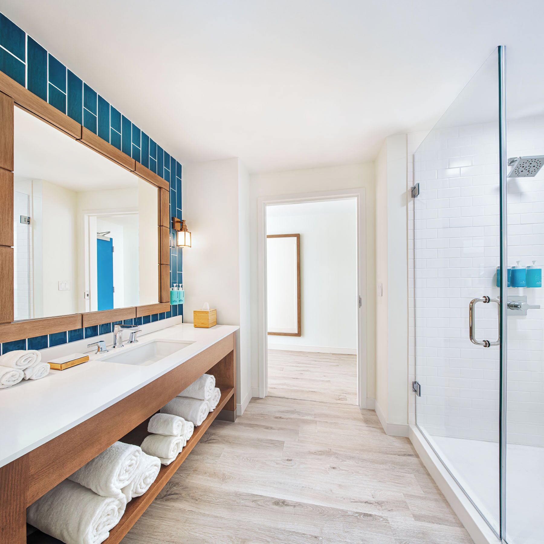 Un baño moderno con un espejo grande, lavamanos dobles y cabina de ducha de vidrio.