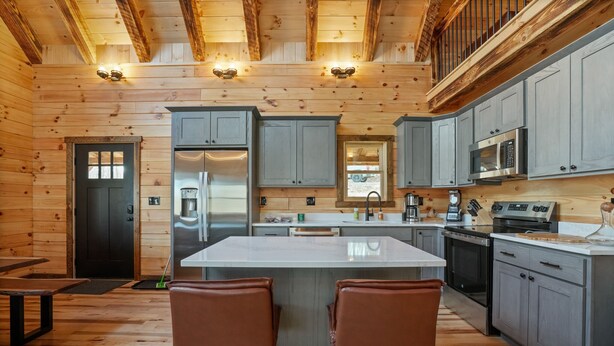 A modern kitchen with wooden walls, a central island, and grey cabinets. - Frog Hill | Hocking Hills, EV Charger, Hot Tub (Logan)