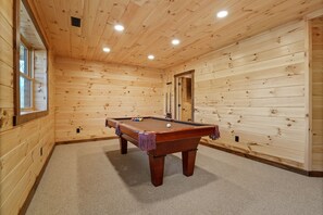A wooden-paneled room with a pool table, carpeted floor, and a door leading to another room. - Frog Hill | Hocking Hills, EV Charger, Hot Tub (Logan)