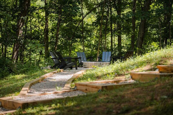 A forested area with a gravel path leading to a seating area with benches. - Frog Hill | Hocking Hills, EV Charger, Hot Tub (Logan)