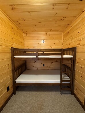 A bunk bed room with wooden walls and a carpeted floor. - Frog Hill | Hocking Hills, EV Charger, Hot Tub (Logan)