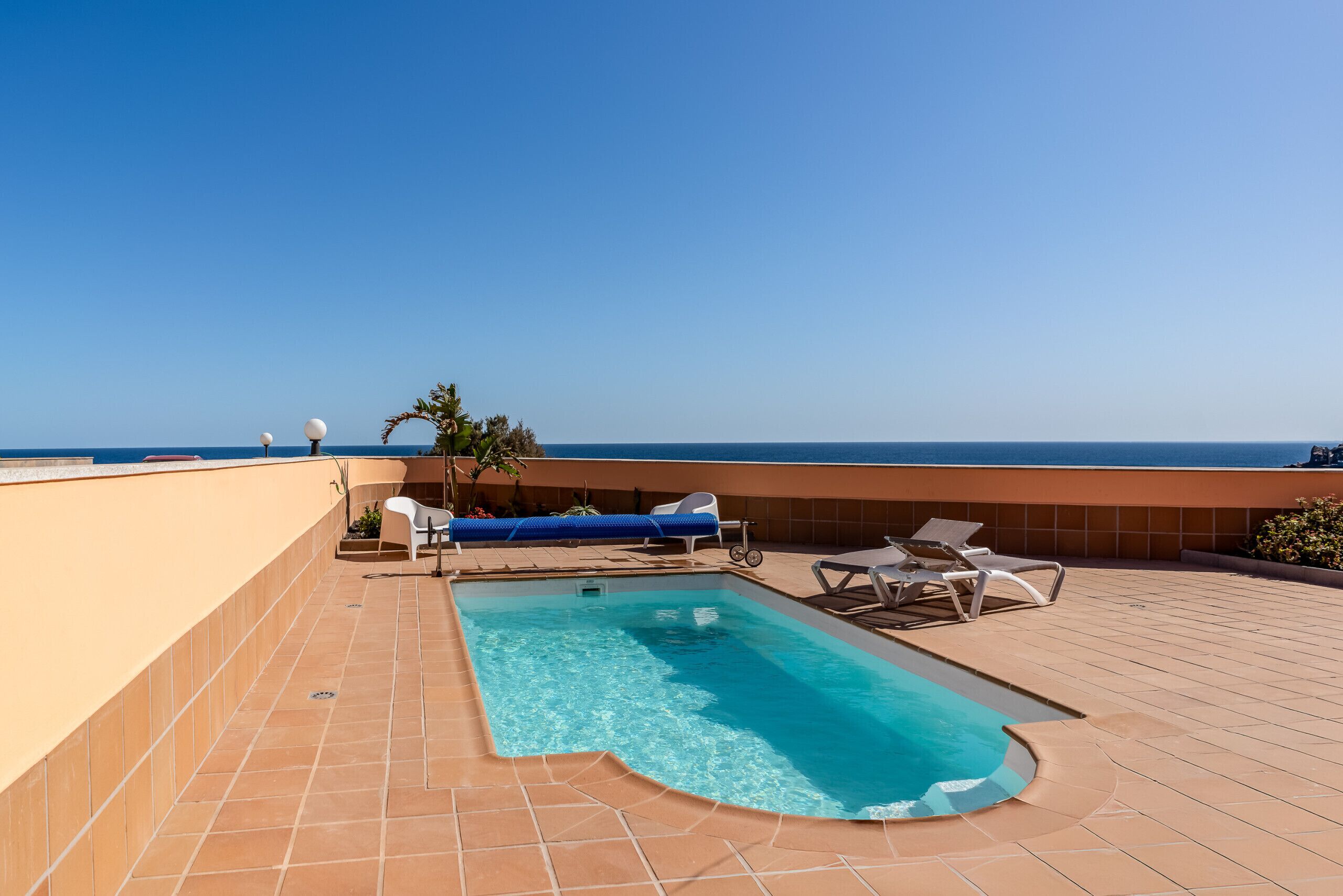 Une piscine sur le toit, avec une eau d’un bleu cristallin, entourée de chaises longues et offrant une vue sur l’océan.