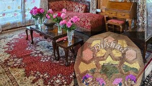 Una habitación tradicional con alfombra estampada, un sofá, una mesa con flores y una araña.