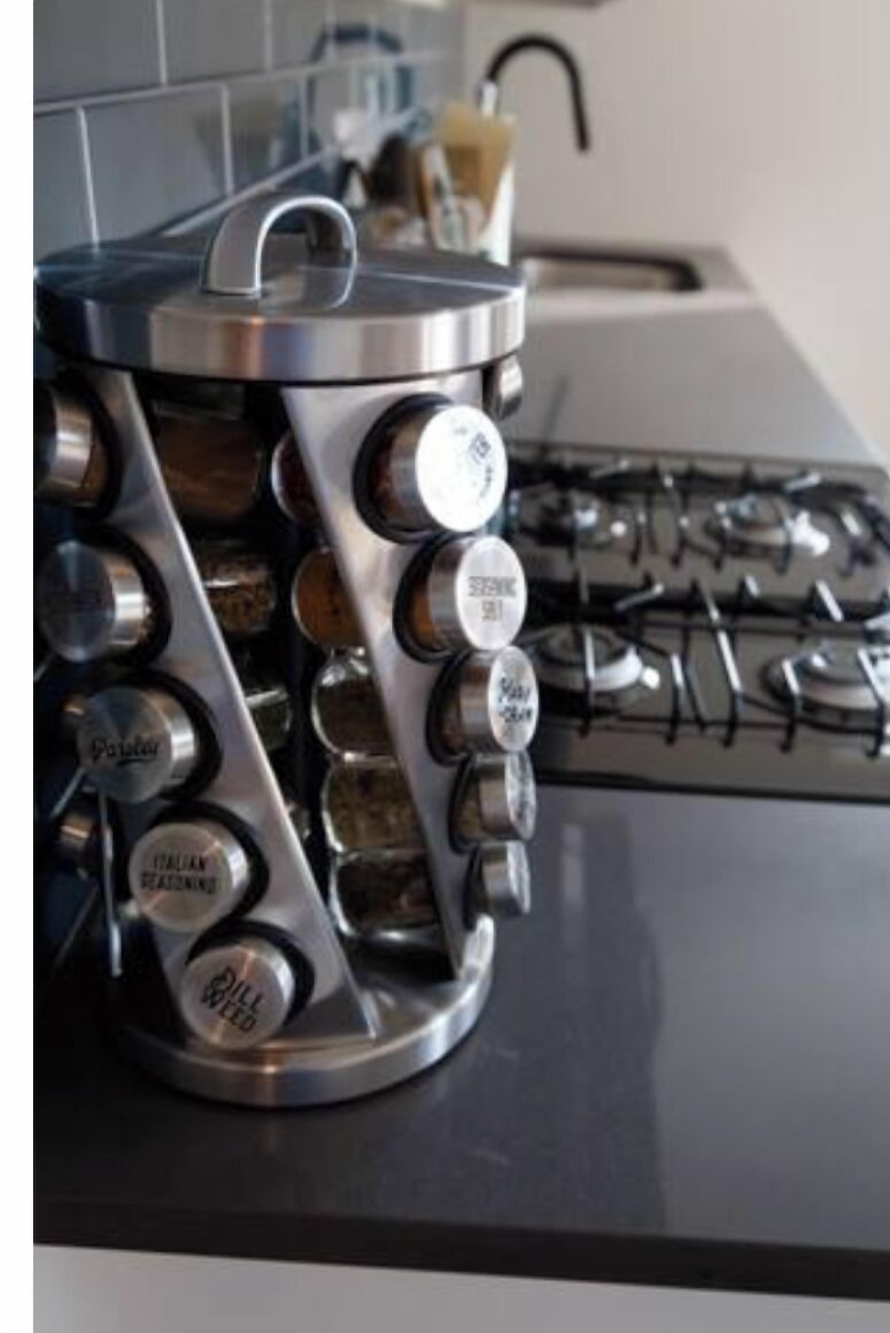 A kitchen with a modern stove and a stainless steel spice rack with multiple compartments.