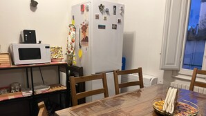 Una zona de menjador amb taula de fusta, cadires, microones, nevera i finestra amb vistes.