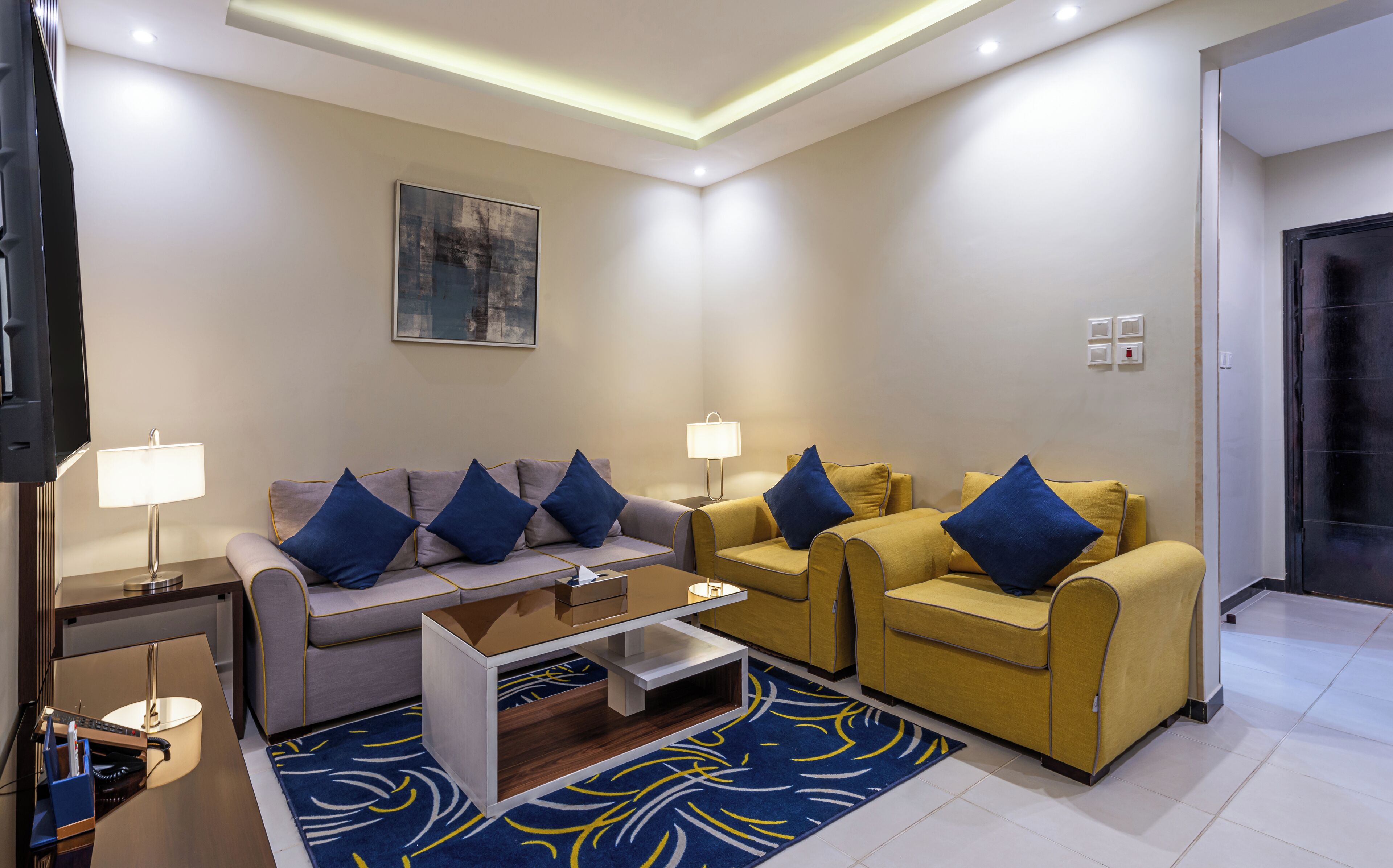 A modern living room with a sofa, armchairs, a coffee table, and a TV.
