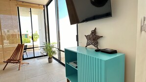 A modern living room with a teal console table, a mounted TV, and a wooden bench.