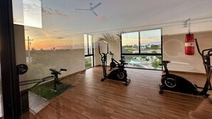 A spacious room with a large window, wooden flooring, and multiple exercise bikes.