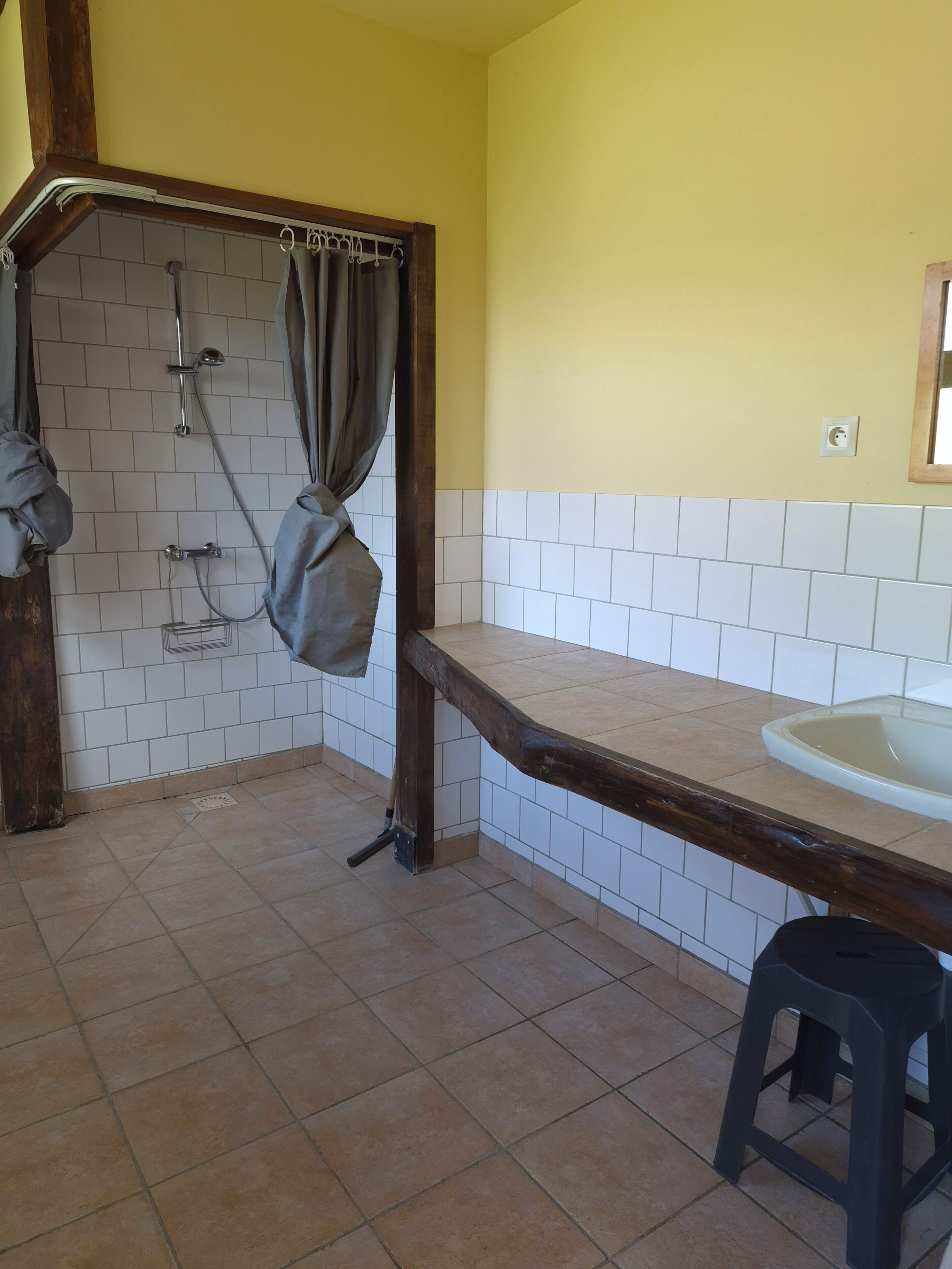 Une salle de bain avec une douche, un lavabo et un tabouret.